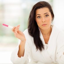 woman with pregnancy test looking unhappy